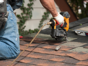 A professional roofing contractor nails down shingles on a home in Anacortes, WA.